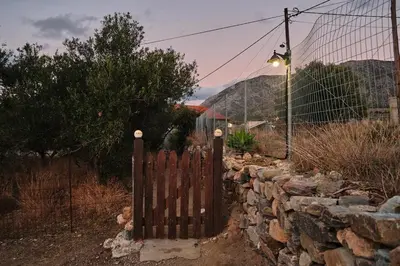 a wooden fence in front of a stone wall at theVotsalo Eco house in Agios Padeleimon