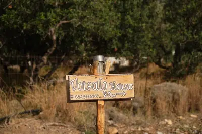 a wooden sign on a pole in a field at theVotsalo Eco house in Agios Padeleimon