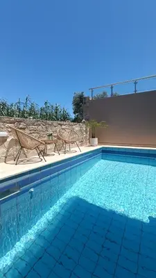 a swimming pool with two chairs and a table at Relax Private Pool House in Maleme
