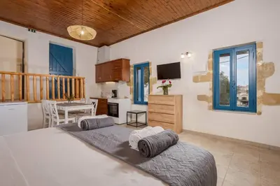 a bedroom with a bed and a kitchen and a balcony at Halases Panorama Villa pvt pool in Alikampos