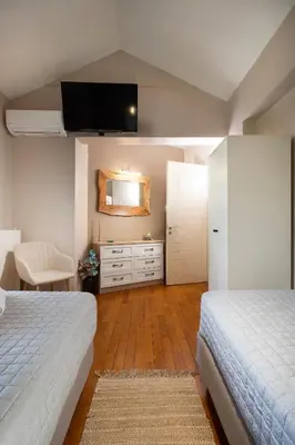 a bedroom with two beds and a tv on the wall at Casa BI LA in Galatás