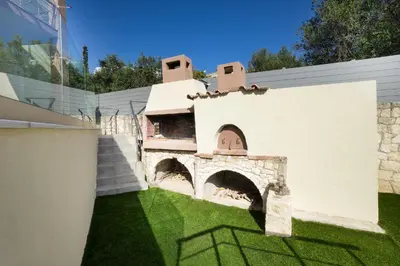 a building with an oven on the side of a yard at Casa BI LA in Galatás