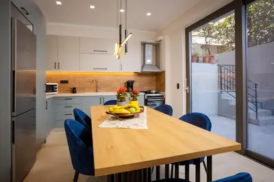 a kitchen with a wooden table and blue chairs at Polixenys home in Daratso