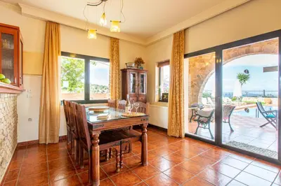 a dining room with a table and a view of a patio at Villa Trouli by Vintage Travel in Metókhi