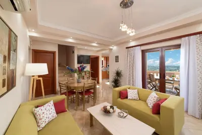 a living room with a yellow couch and a table at Villa Halepi by PosarelliVillas in Gavalochori