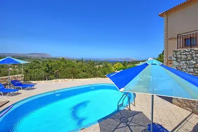 a blue umbrella sitting next to a swimming pool at Villa Halepi by PosarelliVillas in Gavalochori