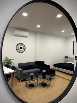 a mirror reflecting a living room with a couch and a clock at Breezy Sea View Appartment in Chania Town