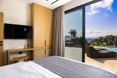 a bedroom with a bed and a sliding glass door at Etheria Elli Villa, Retreat to Ethereal Luxury and Wellness by etouri in CHQ