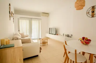 a white living room with a couch and a table at Be Crete - Miramare apartment in Chania Town
