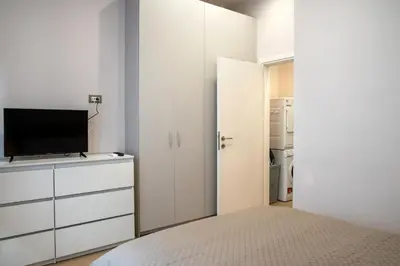 a white bedroom with a bed and a tv at Stelina Apartment in Chania Town