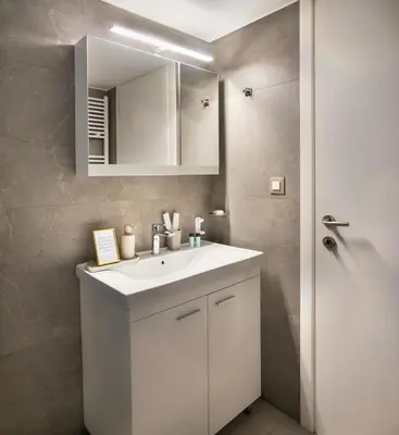 a bathroom with a white sink and a mirror at Stelina Apartment in Chania Town