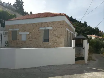 a house with a white fence in front of it at Stone Villa Aori in Pemónia