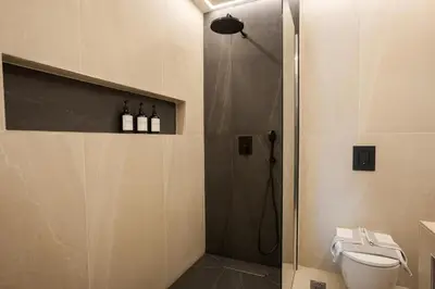 a bathroom with a shower with a toilet and bottles of wine at Theni City Apartment by Zen Estate in Chania Town