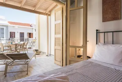 a bedroom with a bed and a balcony with a table at Crescendo Splantzia in Chania Town