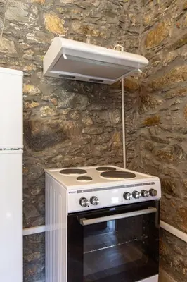 a stove top oven in a kitchen with a stone wall at Vavouledo Village House in Khamalévri