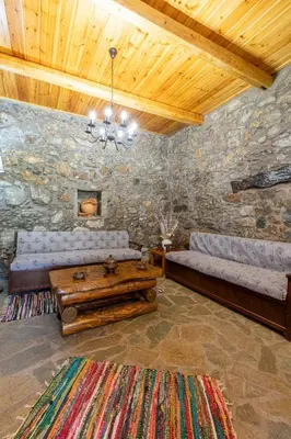 a living room with two couches in a stone wall at Vavouledo Village House in Khamalévri