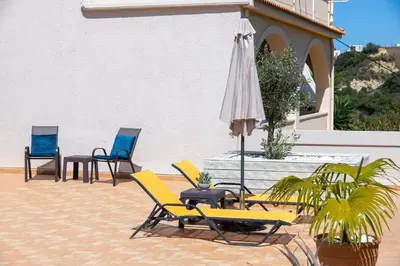 a group of chairs and an umbrella on a patio at Lucia's Home in Stalos
