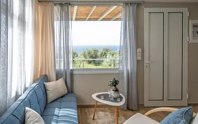 a living room with a blue couch and a large window at View West Elafonisi house in Livadia