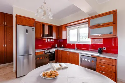 a kitchen with red cabinets and a table with a plate of bread at Villa Avelios in Karefilianá