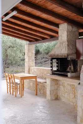 a patio with a table and a stone fireplace at Villa Avelios in Karefilianá