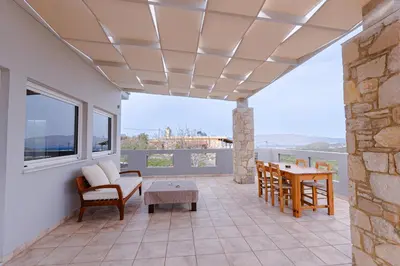 a living room with a table and chairs and a balcony at Villa Avelios in Karefilianá