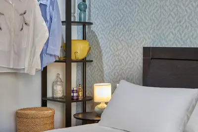 a bedroom with a bed and a shelf with a lamp at Katsambas Apartment - Cozy Retro-Luxury with Balcony in Chania Town