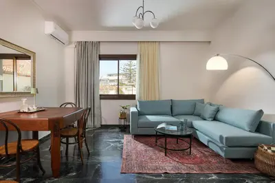 a living room with a blue couch and a table at Katsambas Apartment - Cozy Retro-Luxury with Balcony in Chania Town