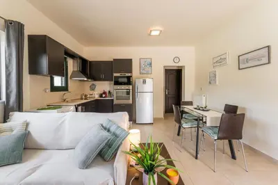 a living room with a white couch and a kitchen at Casa Barbara in Stalos