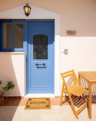 a blue door with a welcome sign next to a chair at Bella Apartment in Chania Town