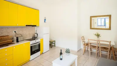 a kitchen with yellow cabinets and a table and a dining room at Bella Apartment in Chania Town