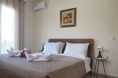 a bedroom with a bed with white sheets and flowers on it at Tzei House - 5min drive to beach in Perivólia