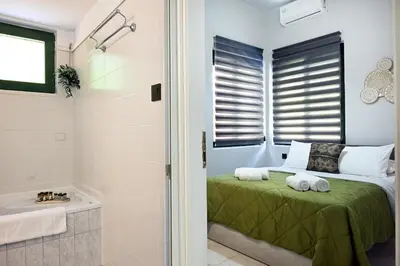 a bedroom with a bed and a shower and a tub at El Dorado Corner with Hot Tub in Chania Town