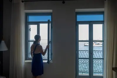 a woman looking out of a window at the ocean at Elia Zampeliou Hotel in Chania Town
