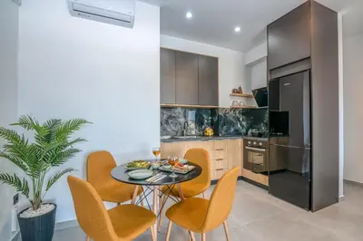 a dining room with a table and chairs and a kitchen at Gems - Stunning 2BR Apts - Steps from the Beach! in Kissamos