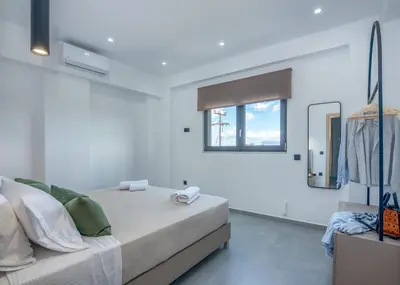 a white bedroom with a bed and a window at Gems - Stunning 2BR Apts - Steps from the Beach! in Kissamos