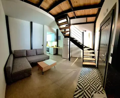 a living room with a couch and a spiral staircase at Mposkini house - next to Chania town center in Chania Town