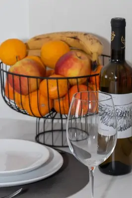 a basket of fruit with a bottle of wine and a glass at Lumea Apartment in Chania Town