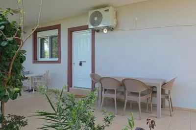 a patio with a table and chairs and a fan at Chania Garden Retreat in Souda