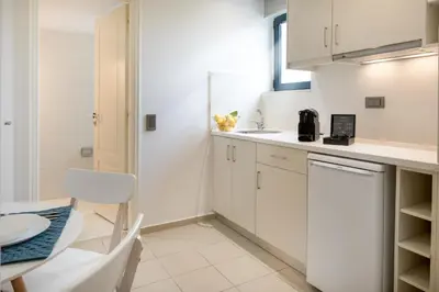 a kitchen with white cabinets and a sink and a table at Forum City Apartments in Chania Town