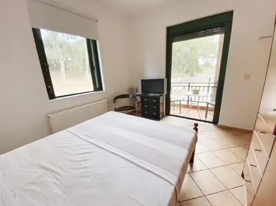 a bedroom with a large white bed and a balcony at Green door in Nerokoúros