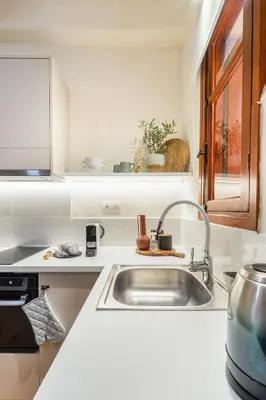 a white kitchen with a sink and a window at Maisonette in center of Chania with roofgarden! in Chania Town