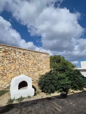 a stone wall with an oven in front of a building at Aldea Apartments in Palio Gerani