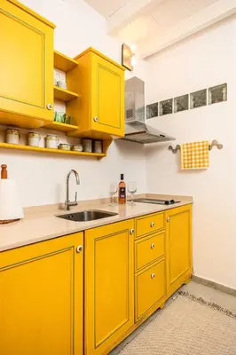 a yellow kitchen with yellow cabinets and a sink at Romantic Maisonette in Chania Town
