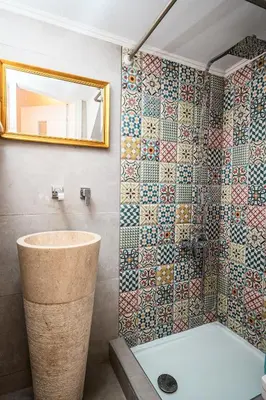 a bathroom with a tub and a mosaic wall at Romantic Maisonette in Chania Town