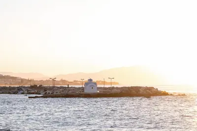 a lighthouse on a small island in the water at Paradise for Couples, Next to Soothing Waves in Galatás
