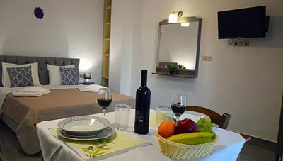 a table with a bottle of wine and a basket of fruit at Tile apartments 1 in Agia Marina Nea Kydonias