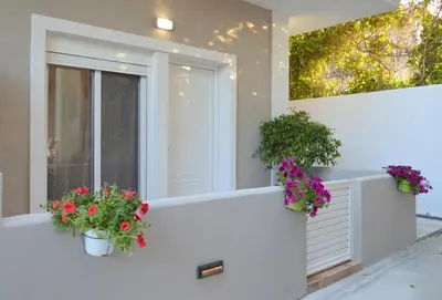 a house with two potted flowers on a balcony at Tile Apartments 2 in Agia Marina Nea Kydonias