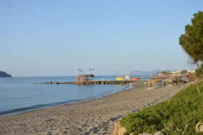 a sandy beach with a pier in the water at Tile Apartments 3 in Agia Marina Nea Kydonias
