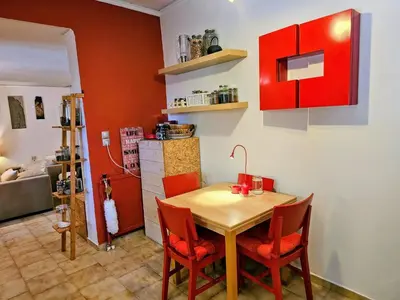 a dining room with a table and red cabinets at Zen House with Fairytale Garden & Sea View in Daratso