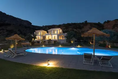 a swimming pool with chairs and umbrellas in front of a house at Libyan Mare in Palaiochóra